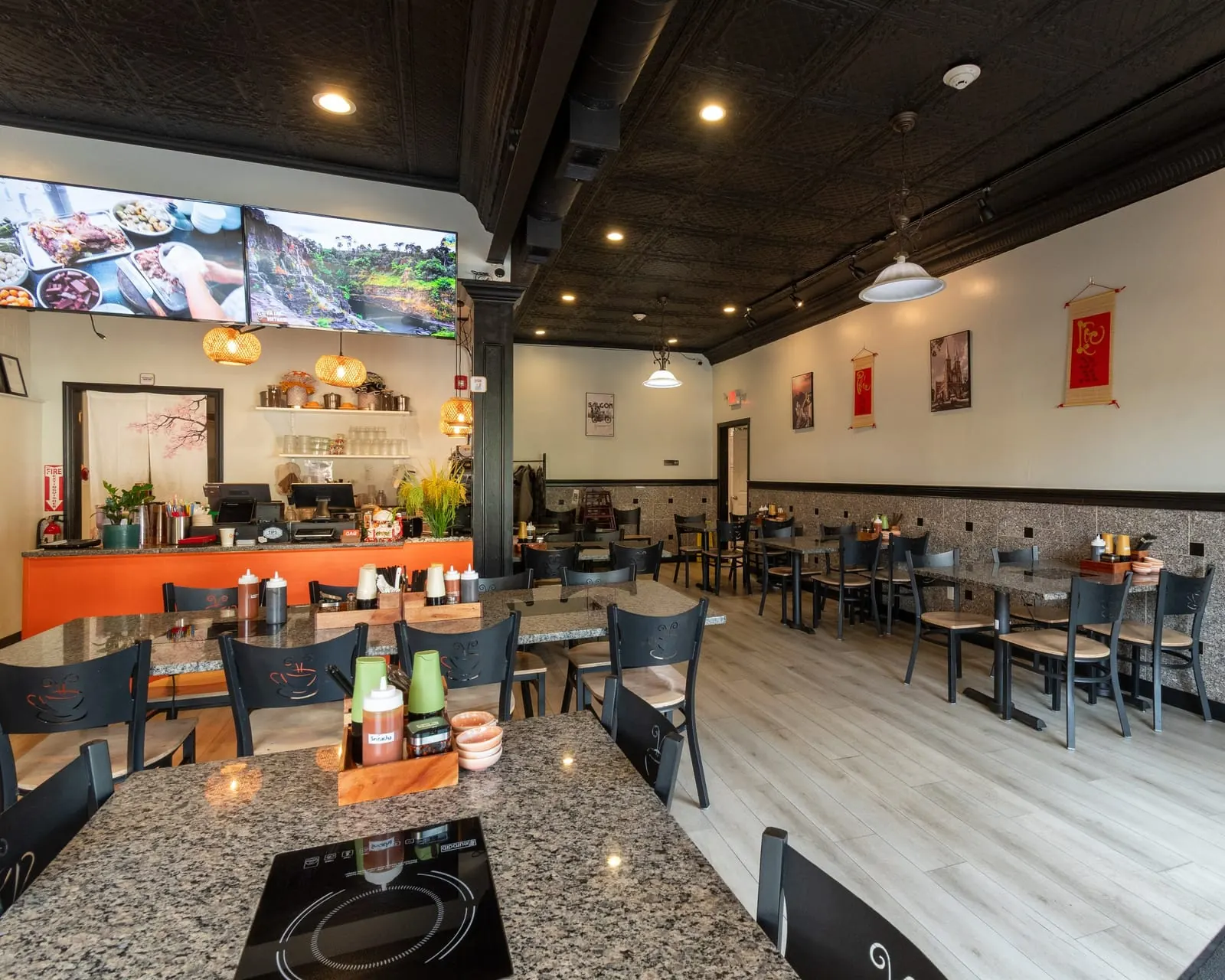 Dining room at Gạo Vietnamese Kitchen with granite tables, a pressed-tin ceiling and rattan pendant lights over the counter