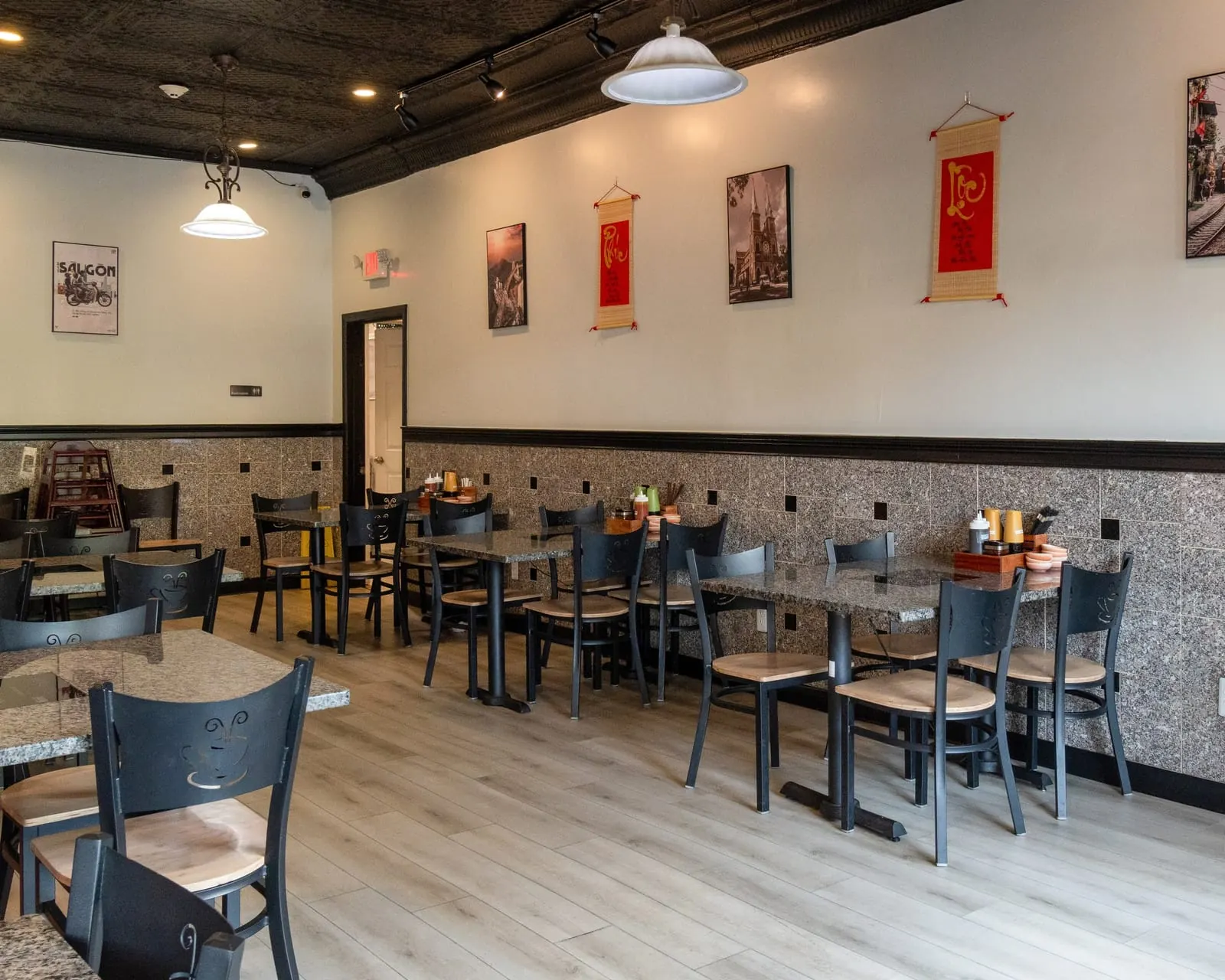 Wall of the Gạo dining room with a vintage Saigon poster and red Phúc–Lộc calligraphy scrolls