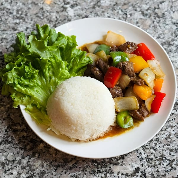 Gạo Vietnamese Kitchen's Shaking Beef with bell peppers, onions, rice, and lettuce on a white plate.